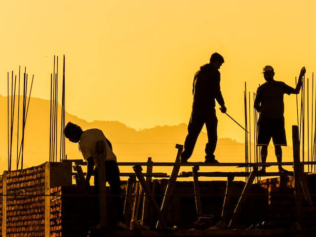 A silouette of builders working in a construction site.
